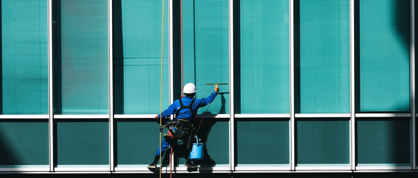 Foto: Gebäudereiniger putzt Fenster eines Hochhauses